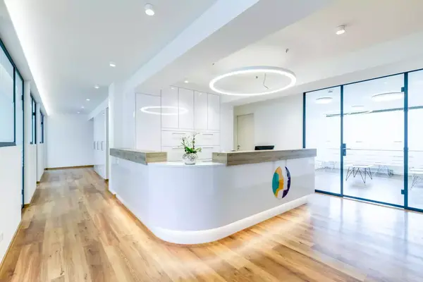 Heller Empfangsbereich einer modernen Arztpraxis mit Holzfußboden und Glaswänden.