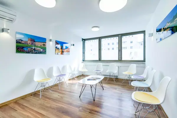 Heller Wartebereich mit modernen Stühlen, Holzboden und großen Fenstern in einer Praxis.